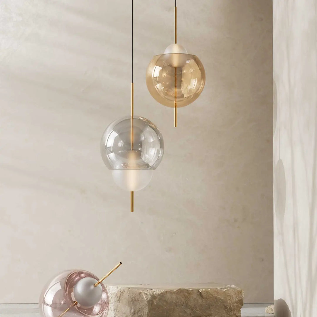 Lampe suspendue galileo avec deux globes modernes en verre clair et ambré suspendus par des tiges métalliques dorées