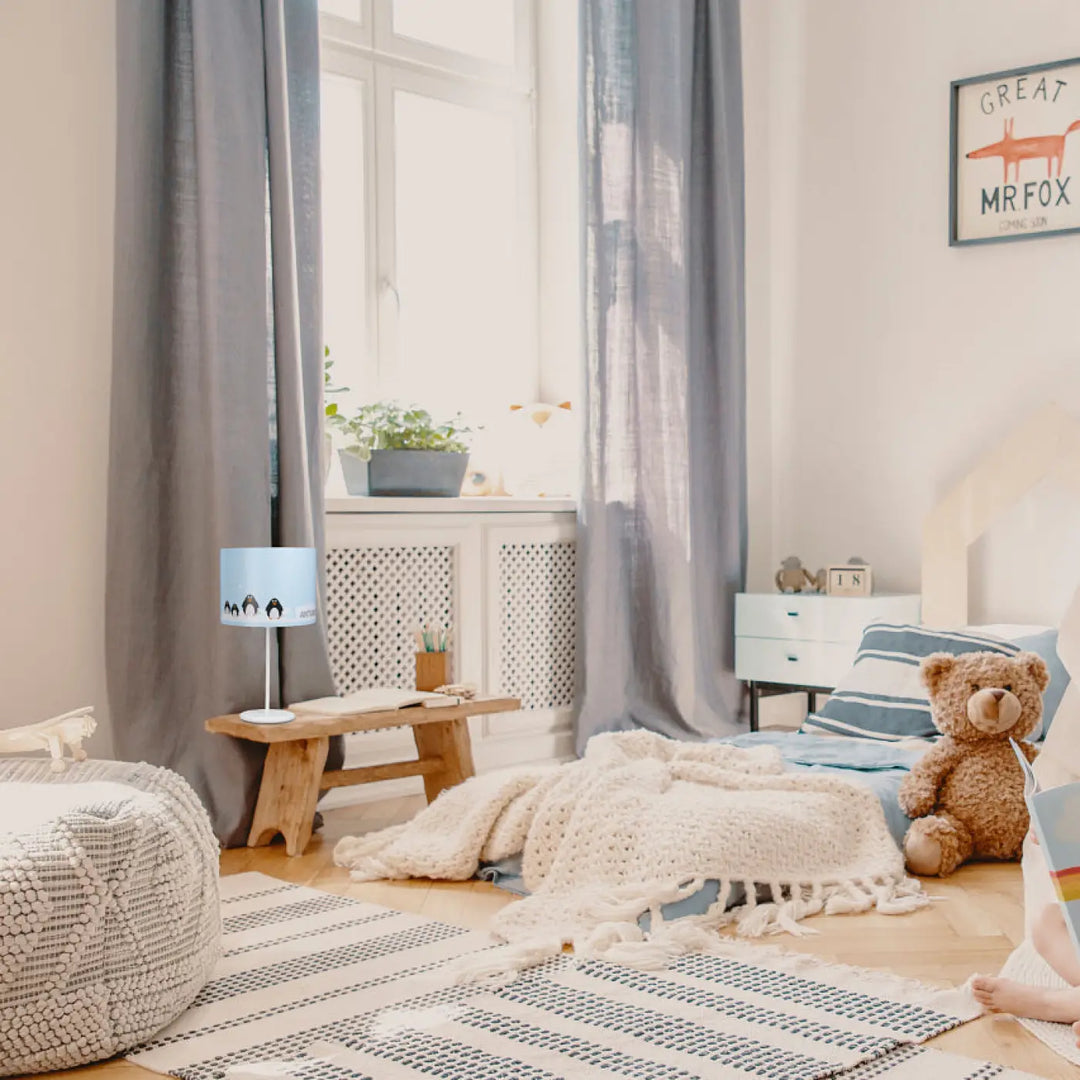 Lampe de table bleu clair avec design aux adorables manchots posée sur un banc en bois dans la collection sweet dreams