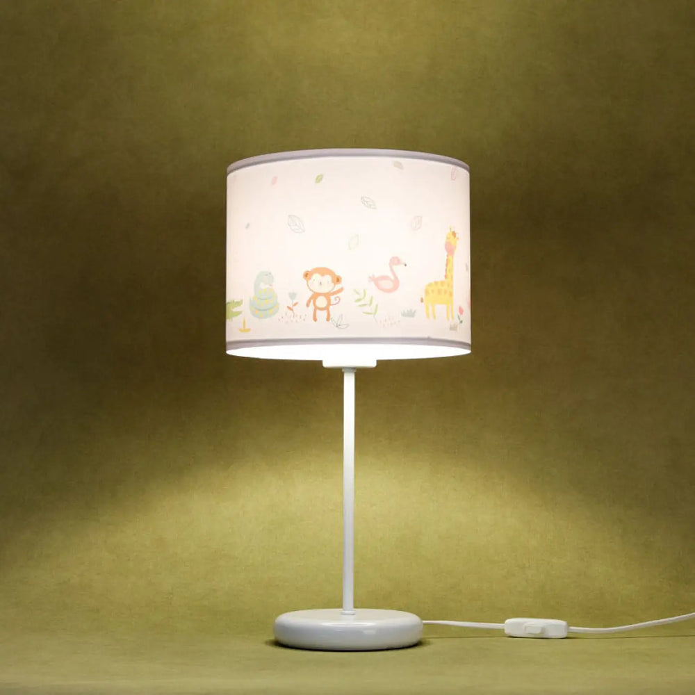 Lampe de table vert clair avec abat-jour cylindrique blanc motif savane coloré sur table blanche