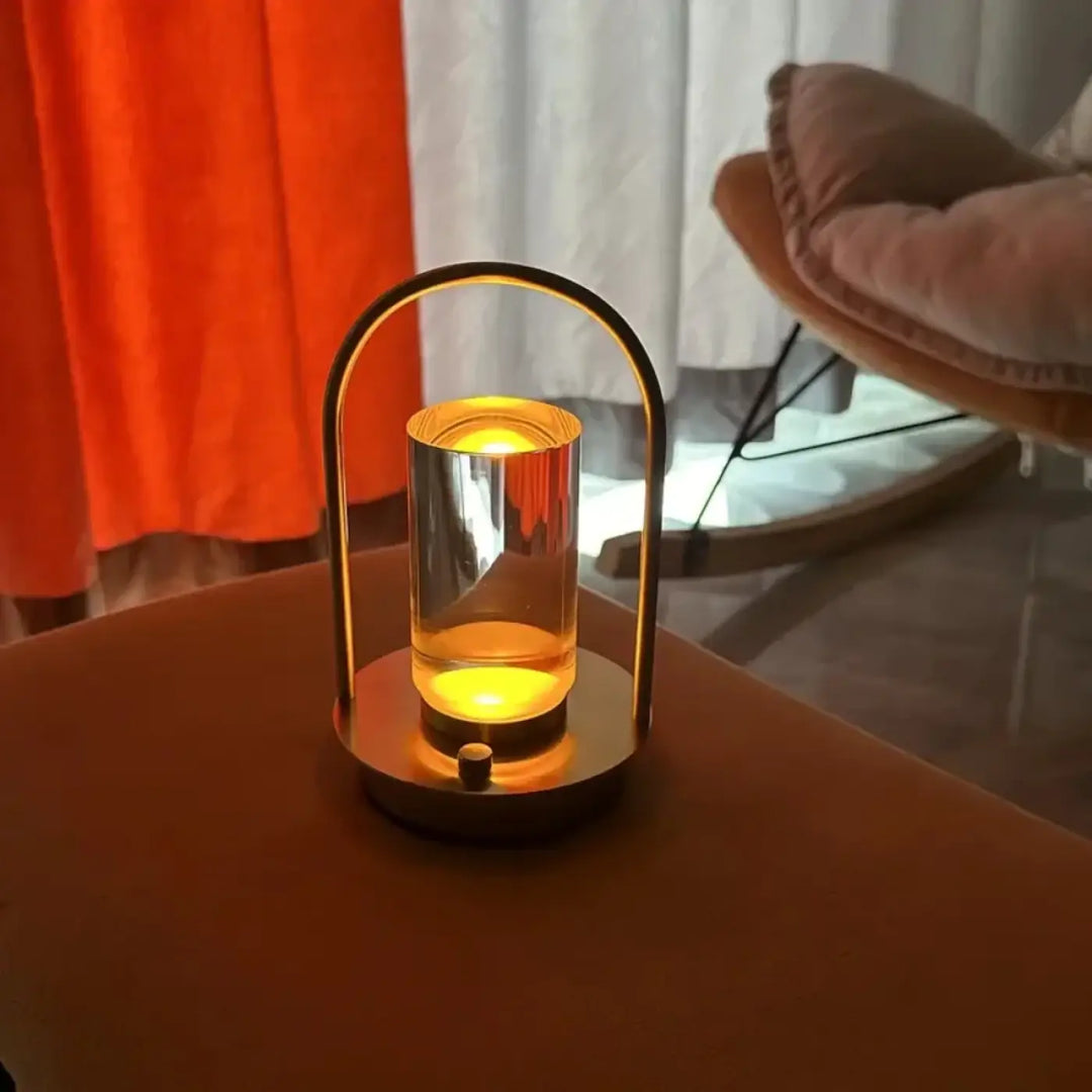 Lampe de table neora avec lumière cylindrique flottante en verre et arche épurée en métal doré émettant une lumière jaune chaleureuse