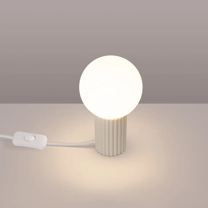 Lampe halo beige avec base cylindrique cannelée en verre laiteux émettant une lumière chaude douce version suspension
