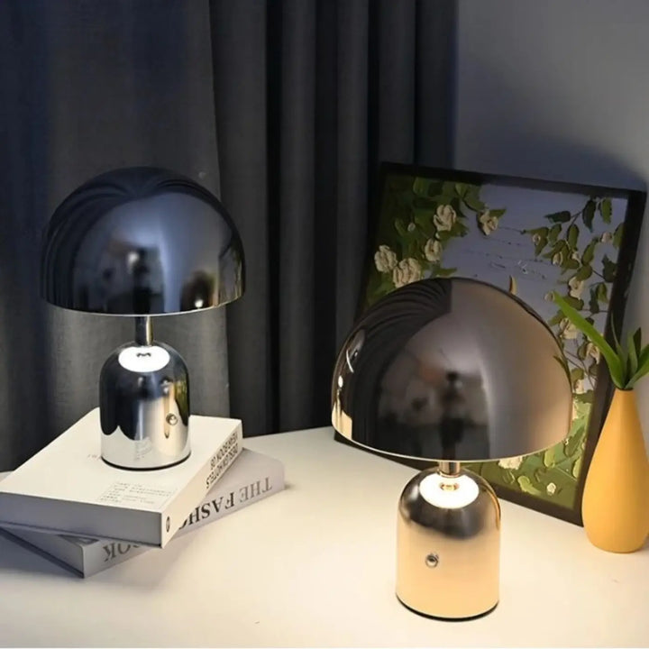 Deux lampes de table modernes à abat en forme de dôme avec finition métallique reflets miroir noir et or sur surface blanche