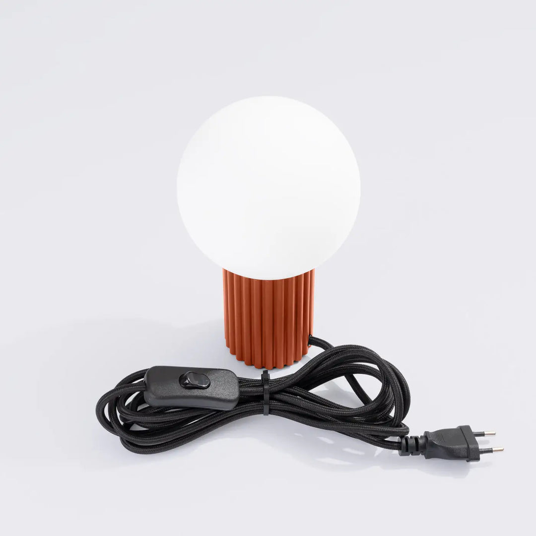 Lampe halo version lampe a poser avec abat-jour sphérique blanc et base cylindrique rouge ochra texturée