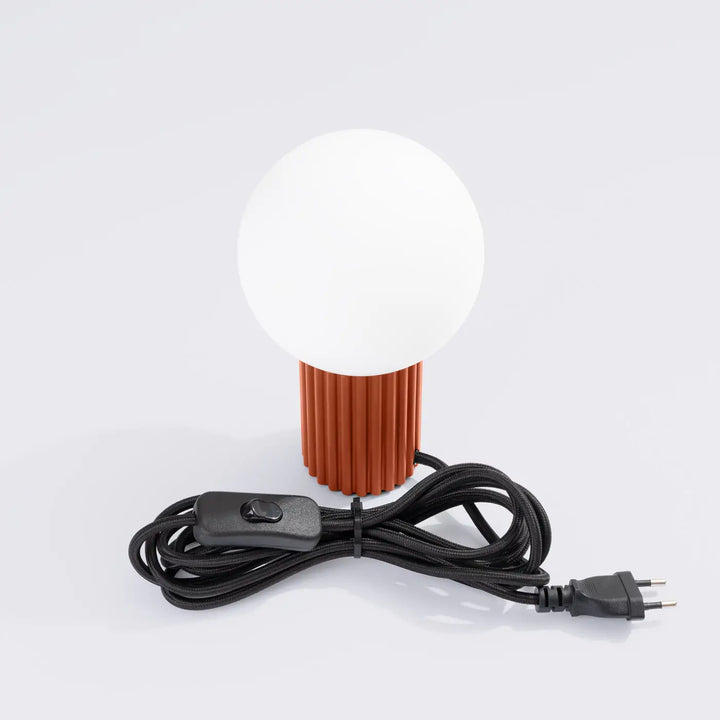 Lampe halo version lampe a poser avec abat-jour sphérique blanc et base cylindrique rouge ochra texturée