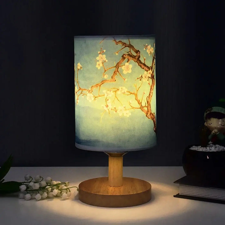 Lampe de table samira cylindrique avec base en bois et motifs fleuris style asiatique sur fond bleu-vert degrade