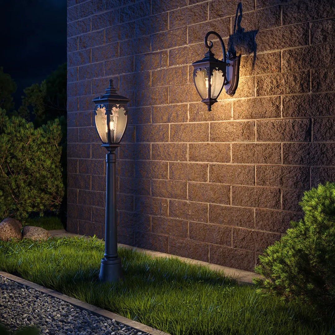 Lampadaire extérieur fleur en fer forgé noir avec lanterne italienne en verre clair pour bord d’une terrasse