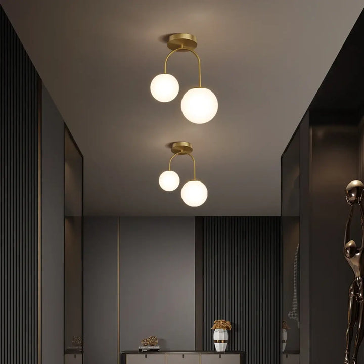 Luminaire plafonnier solia design chic avec deux globes en verre dépoli suspendus par bras métalliques dorés
