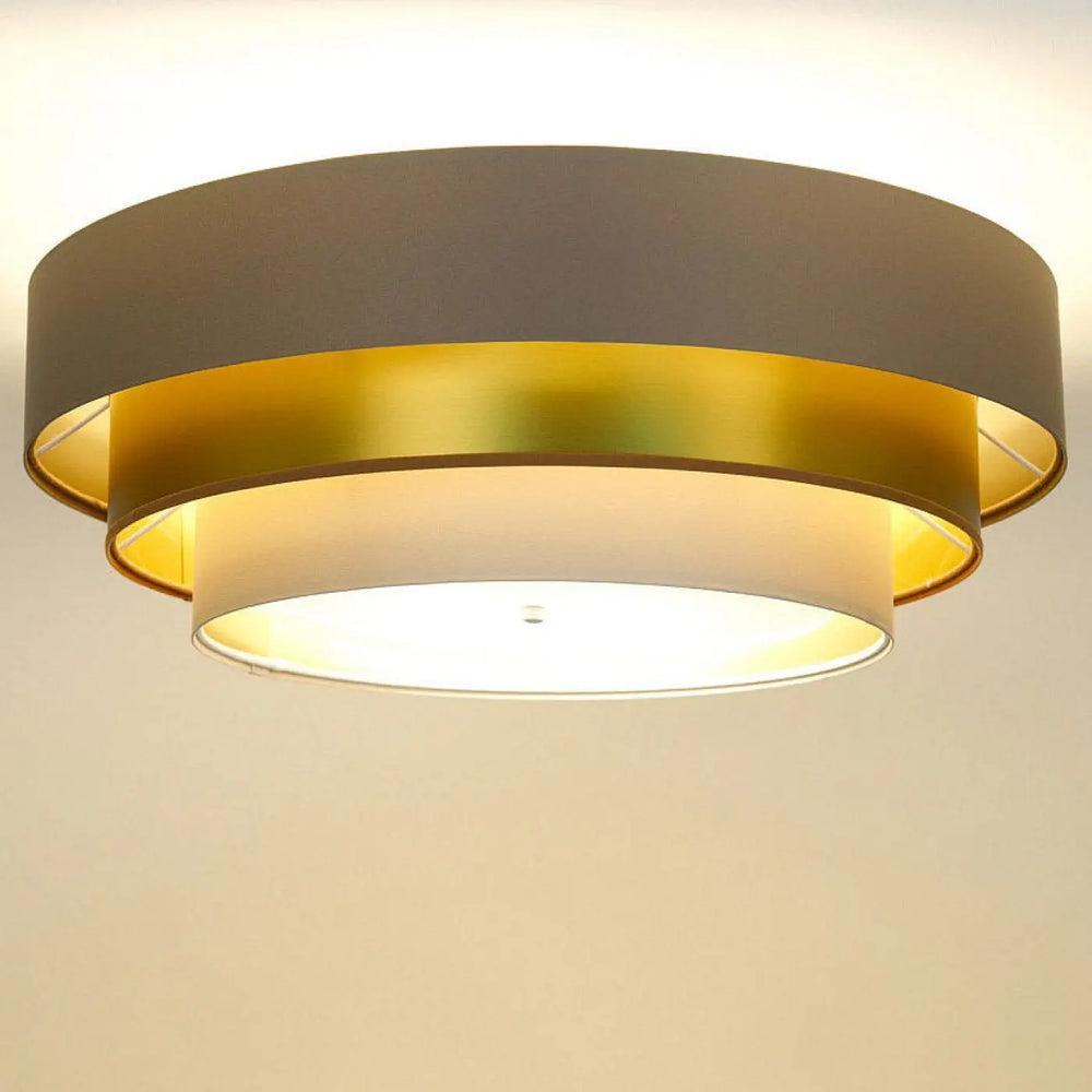 Luminaire plafonnier triniti elegant beige avec design en anneaux métalliques dorés et gris mat émettant une lumière chaude