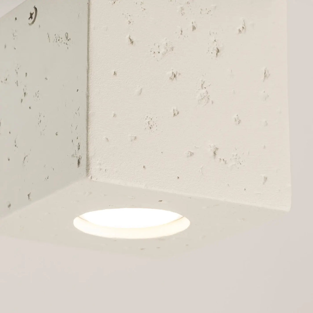 Plafonnier quad design contemporain en béton beige avec lumière encastrée douce dans un mur texturé off-white