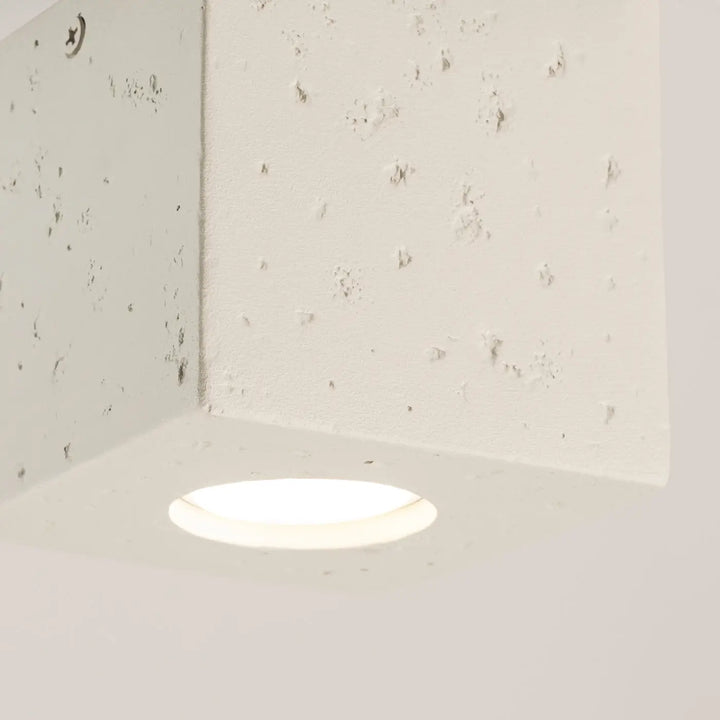 Plafonnier quad design contemporain en béton beige avec lumière encastrée douce dans un mur texturé off-white
