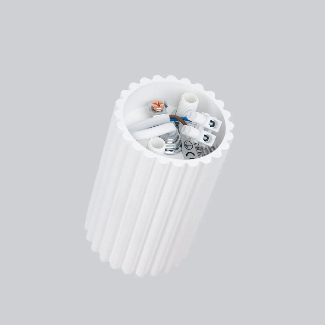Plafonnier karbon blanc cylindre en design minimaliste avec flûtes et bord scallopé montrant câblage interne