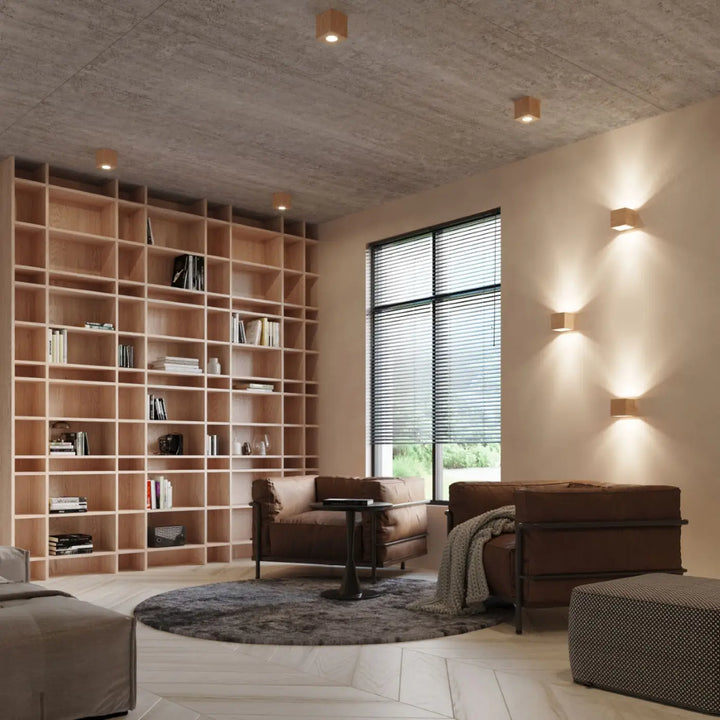 Luminaire plafonnier quad 1 en bois naturel avec ambiance chaleureuse près de fauteuils en cuir brun et couverture texturée