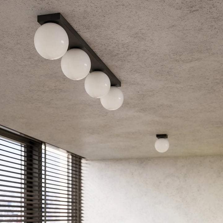 Luminaire plafonnier yoli 1 noir avec quatre globes en verre blanc sphériques classe à part design moderne