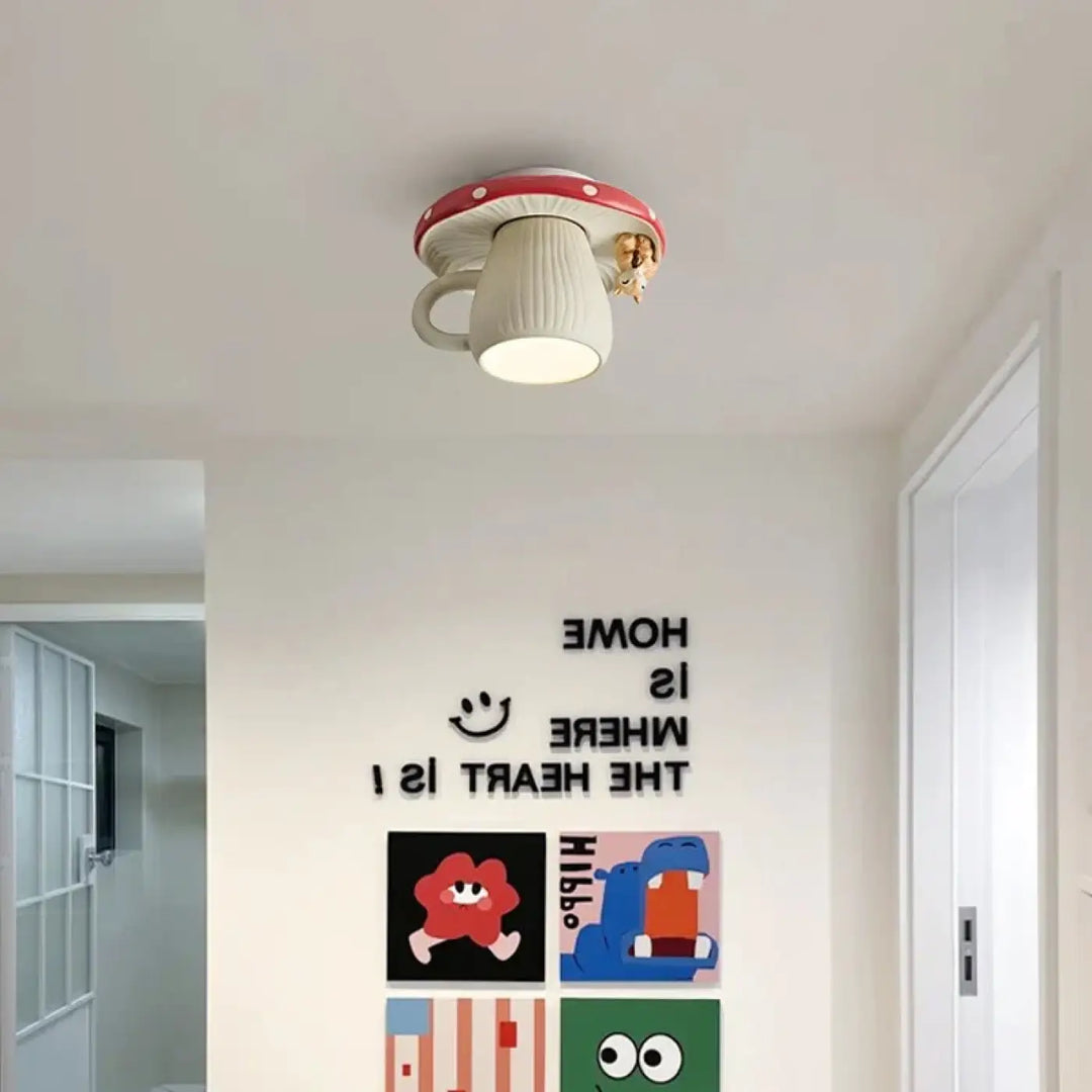 Une lampe de plafond fantaisiste en forme de champignon avec un chapeau rouge et un corps blanc texturé, présentant une petite créature dorée perchée sur son côté.