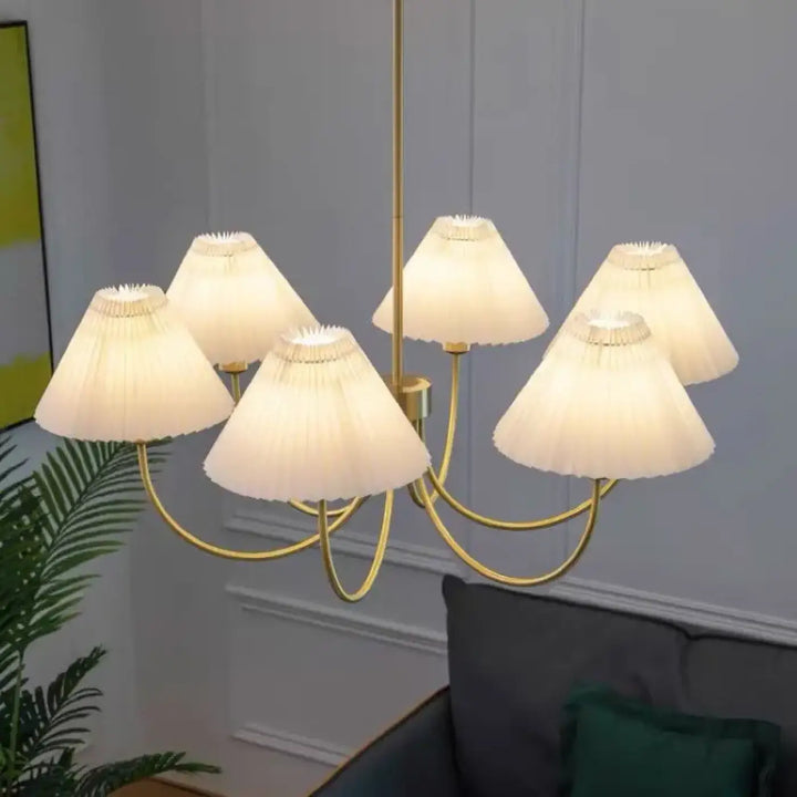 Suspension luminaire sandyra avec six abat-jours en tissu plissé couleur crème et structure dorée, idéale pour salle à manger