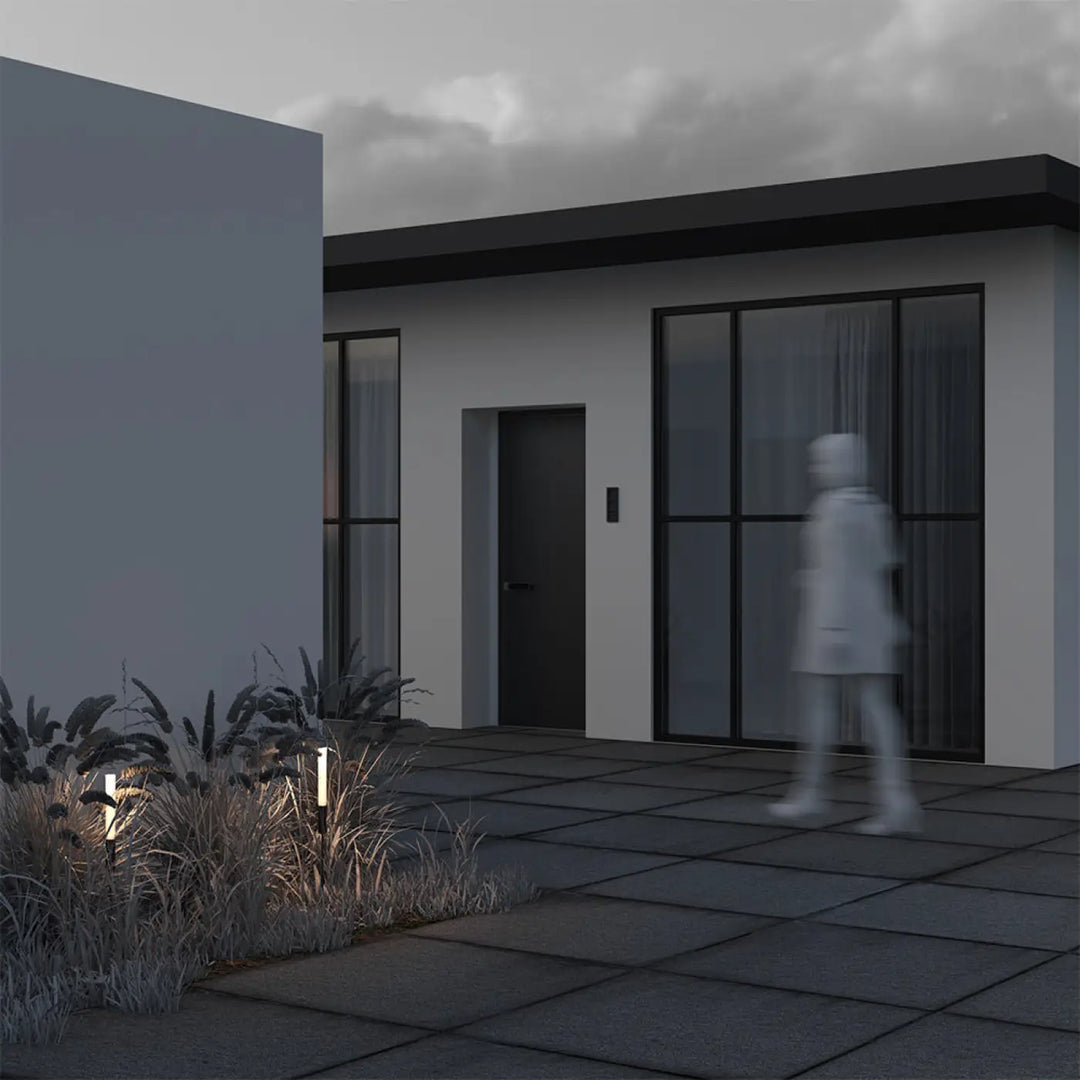 Luminaire extérieur flare tige fine en aluminium noir devant maison moderne avec porte grise et fenêtres noires