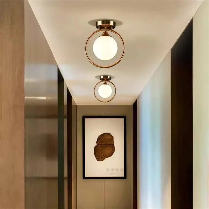 Luminaire plafonnier orbane avec anneau doré et boule lumineuse en verre dépoli pour un plafonnier chic moderne