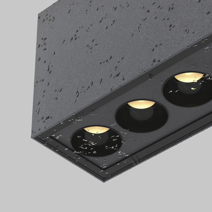 Plafonnier extérieur ares en métal graphite noir avec trois ampoules led chaudes encastré long dune galerie sur surface grise texturée