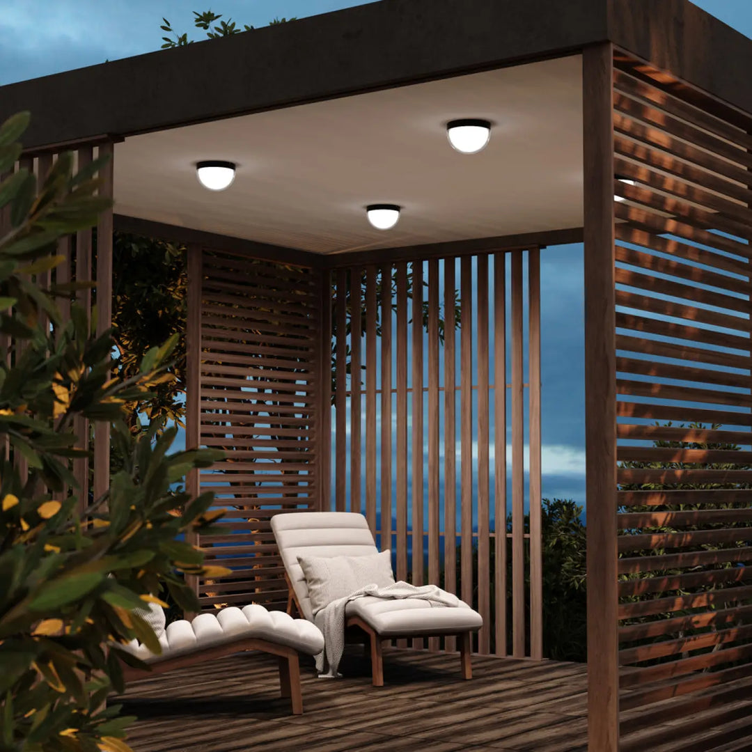 Plafonnier extérieur mon en acier noir avec trois spots encastrés ronds et indice ip65 éclairant une pergola en bois