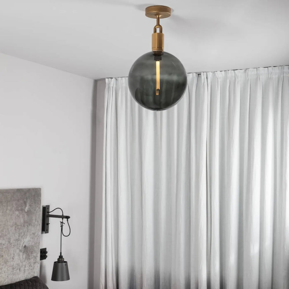 Plafonnier Forked grand modèle à globe fumé, finition laiton, dans un intérieur #couleur_dor