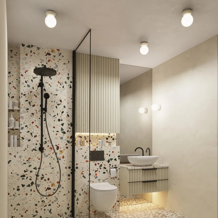 Douchette noire avec flexible et fixations assorties contre un mur terrazzo blanc pour lampe zori et belle décoration