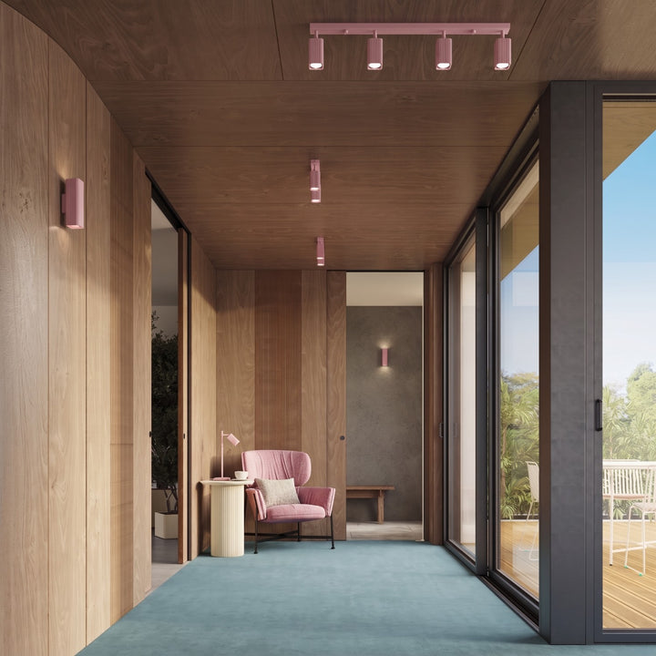 Plafonnier Rayo rose en rampe à spots orientables au plafond d'un couloir