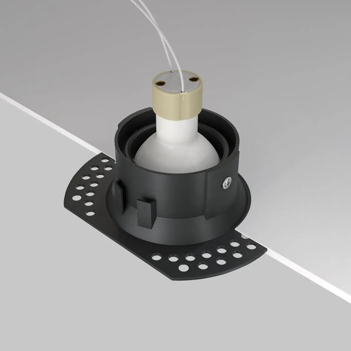Spot encastrable dot avec finition mate noire, base perforée circulaire et ampoule blanche dans collier doré
