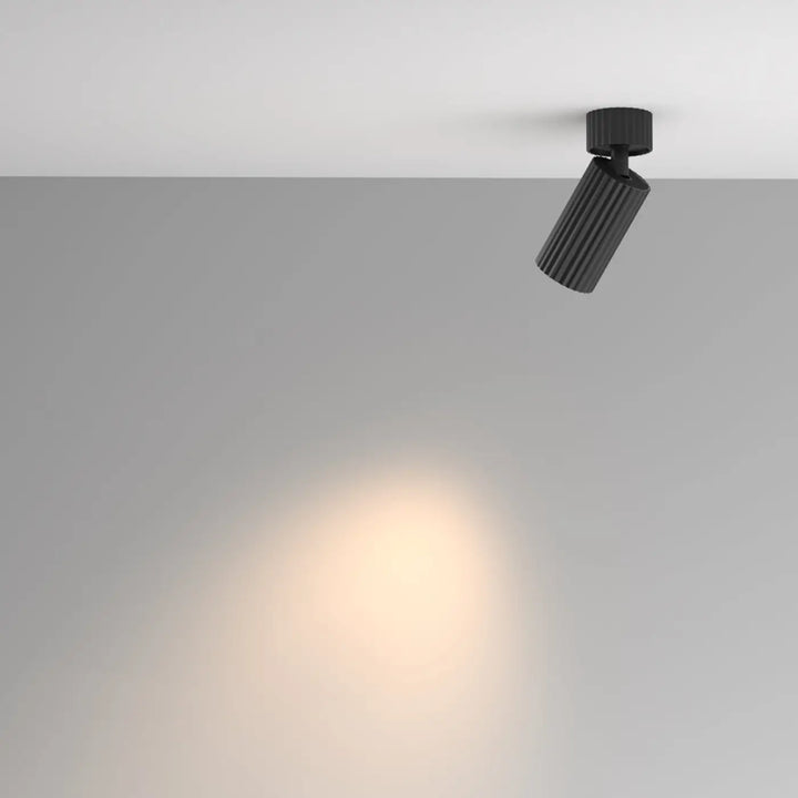 Spot orientable calipso noir cylindre cannelé émettant un faisceau lumineux chaud et focalisé