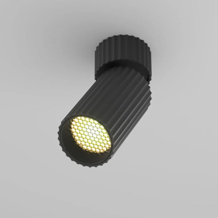 Spot orientable cylindre cannelé noir avec led en nid dabeille émettant une lumière jaune chaude spot orientable calipso