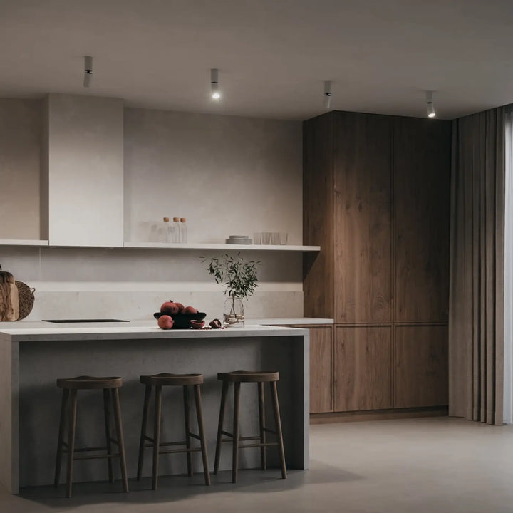 Îlot de cuisine minimaliste spot focus s avec plan de travail blanc mat et tige fine, tabourets en bois foncé
