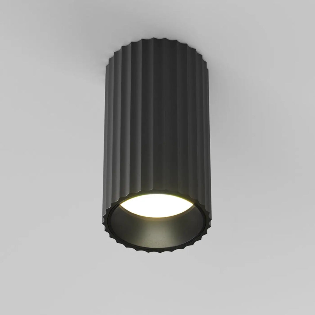 Spot calipso cylindre cannelé noir avec éclairage ciblé et ampoule circulaire chaude en trois finitions