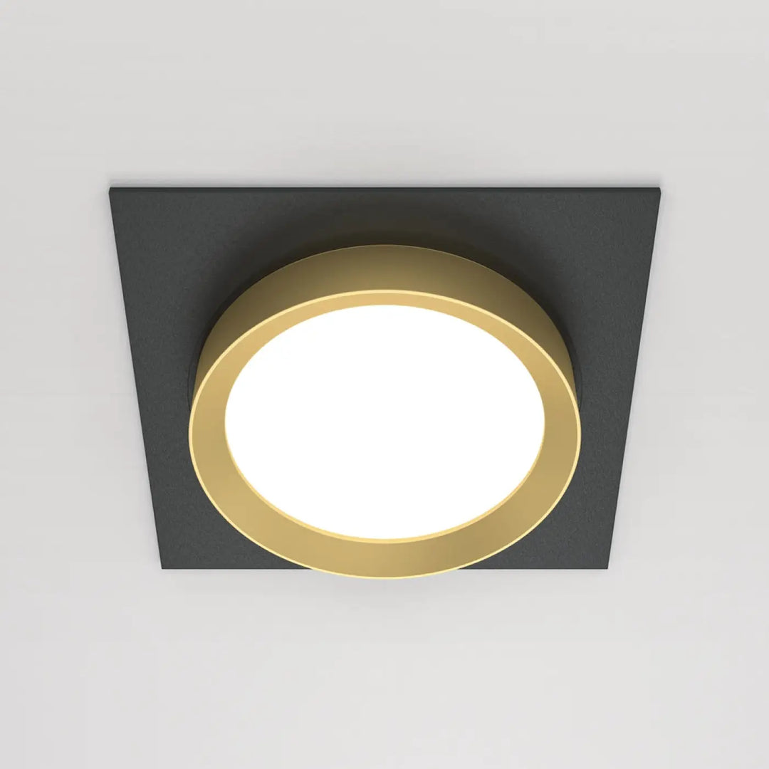 Spot semi-encastré cadre carré avec cadre noir et disque lumineux or entourant centre blanc lumineux