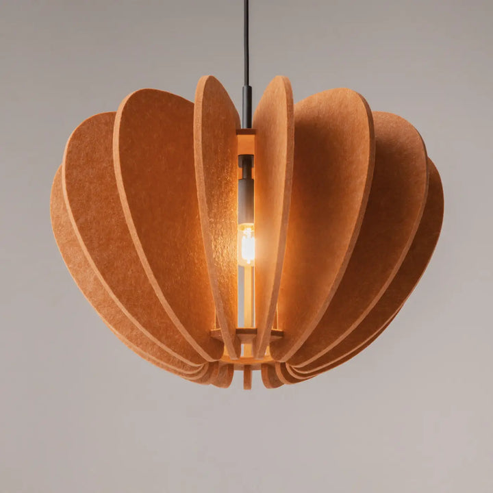 Suspension luminaire cambio coupole en liège texturé chaud au-dessus d’une table avec aluminium noir et ampoule centrale exposée