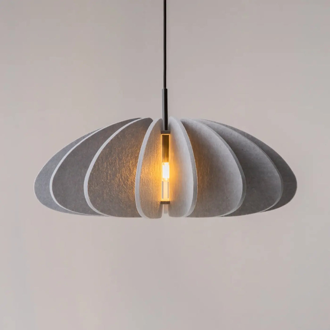 Suspension luminaire cambio en aluminium noir avec abat-jour pétale gris et lumière chaude au-dessus d’une table
