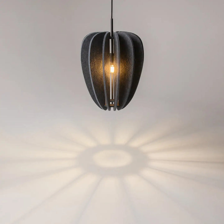 Suspension luminaire cambio en aluminium noir segmented avec une douce lueur au-dessus d’une table et motifs ombrés radiaux
