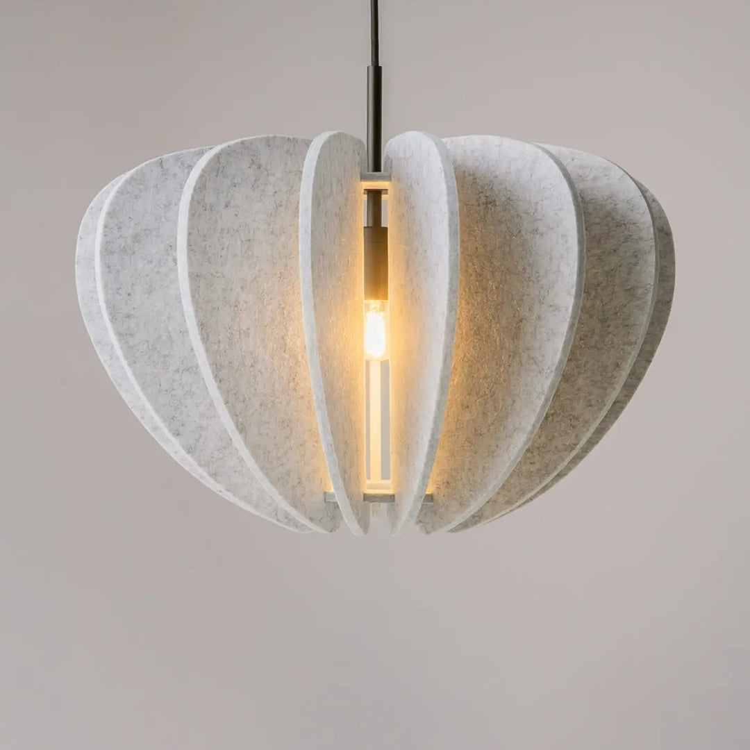 Suspension luminaire cambio avec matériaux feutrés off-white en pétales superposés au-dessus d’une table élégante