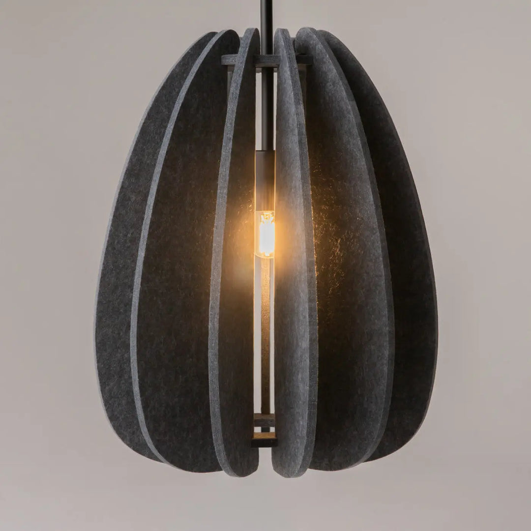 Suspension luminaire cambio en aluminium noir avec panneaux en feutre gris foncé au-dessus d’une table avec ampoule exposée