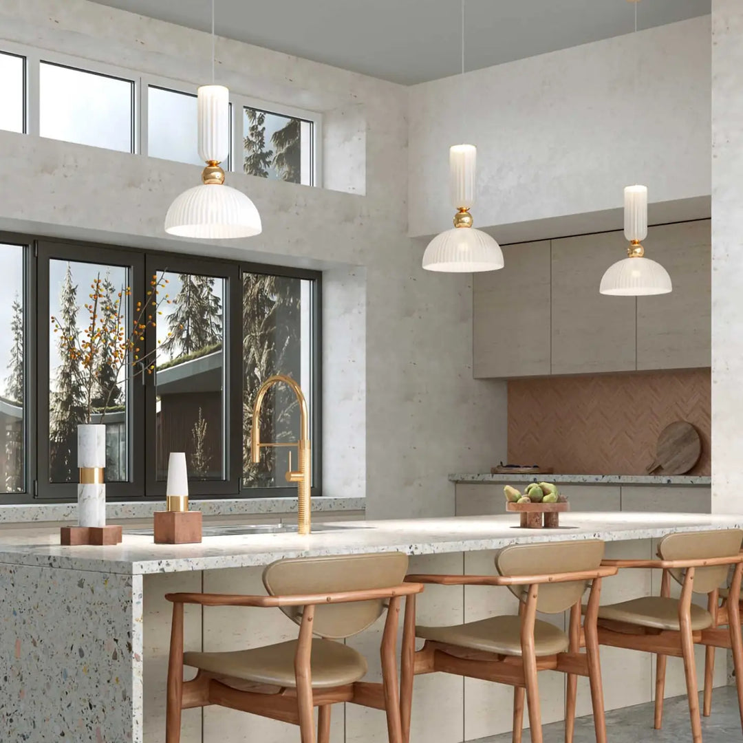Suspension antic avec trois luminaires en verre strié blanc et monture dorée suspendus au-dessus dîlot moderne