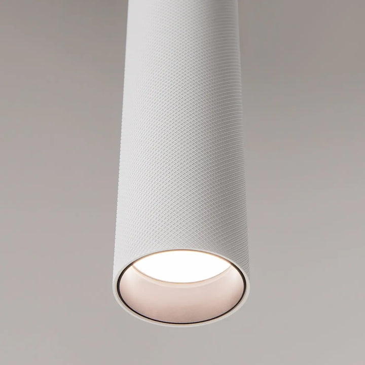 Suspension artisan blanche cylindrique avec surface texturée et ouverture lumineuse, idéale au-dessus d’une table