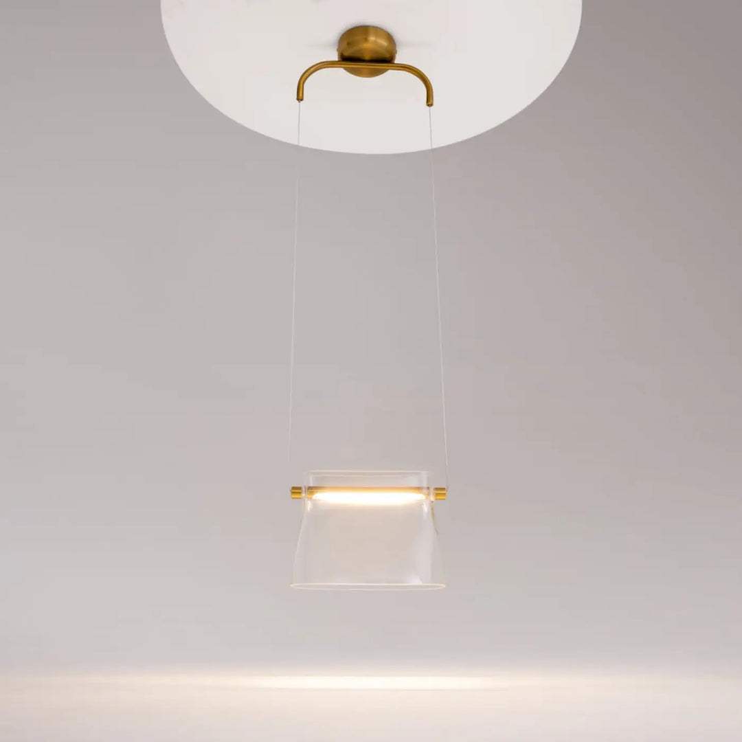 Suspension luminaire cabaret avec verre transparent et accents en laiton au-dessus d’une table moderne