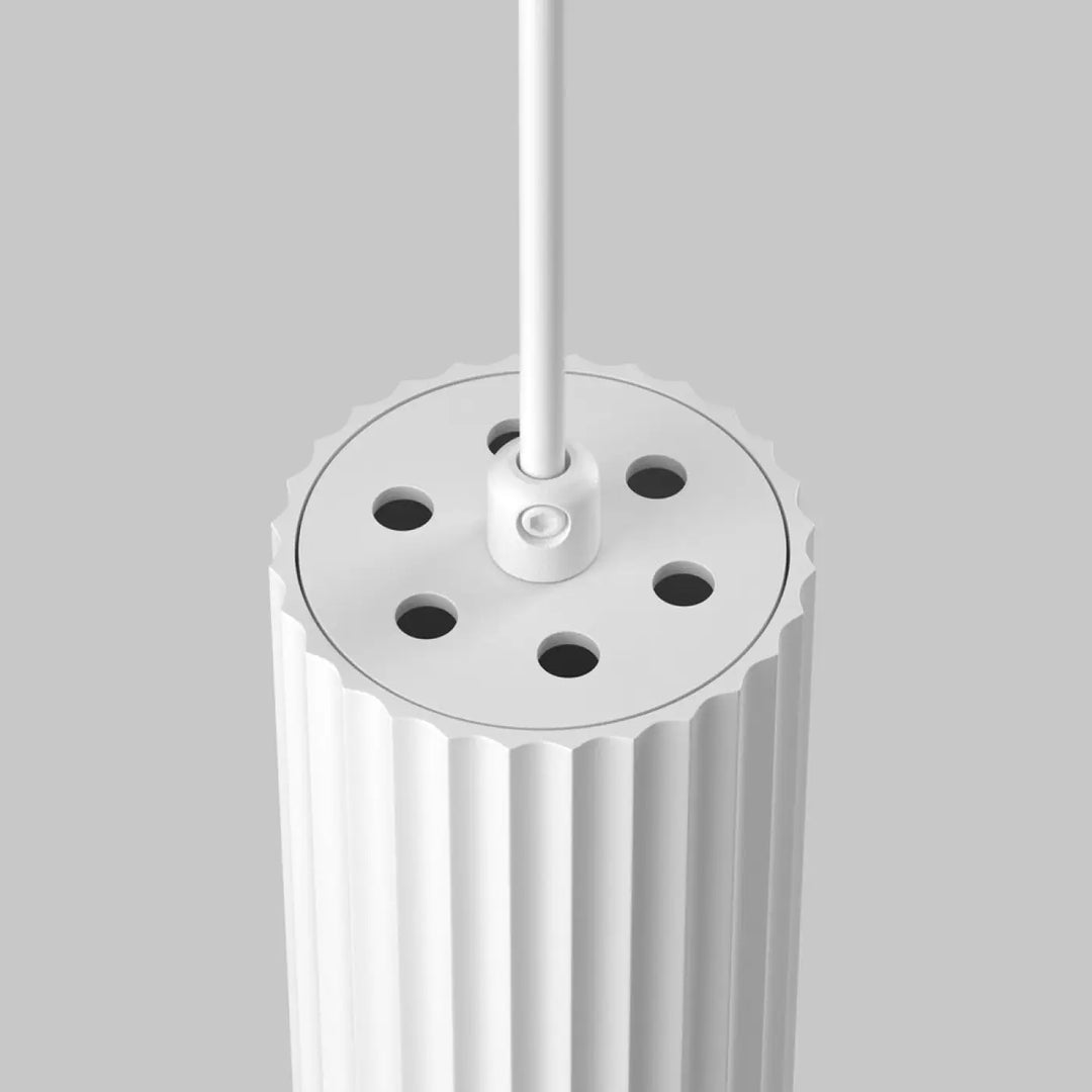 Suspension luminaire calipso blanc au-dessus d’un îlot avec tubes cylindriques à rainures verticales et six trous circulaires au sommet