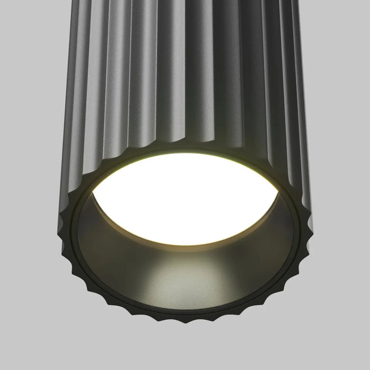 Suspension luminaire calipso tube gris foncé cylindrique à rainures verticales avec bord festonné au-dessus d’un îlot