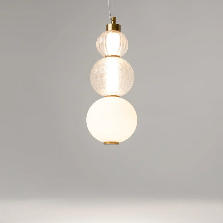 Suspension collar en métal doré avec trois globes en verre texturés offrant une lumière à 360°