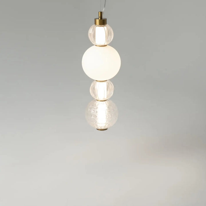Suspension collar avec quatre globes en verre opaques empilés et métal doré offrant une lumière à 360°