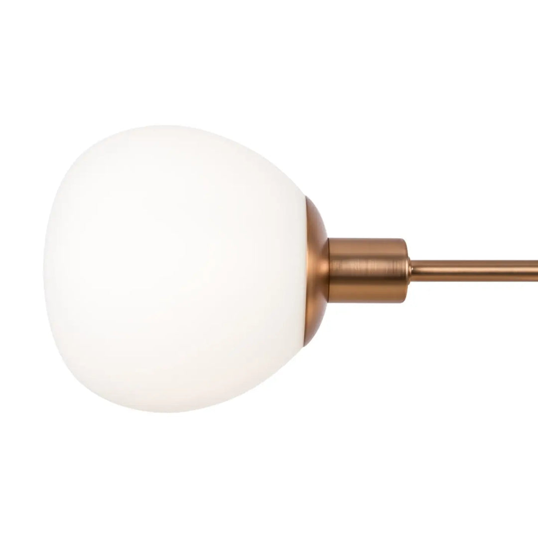 Suspension luminaire erich avec globe en verre blanc givré et tige cuivre brossé au-dessus d’une table