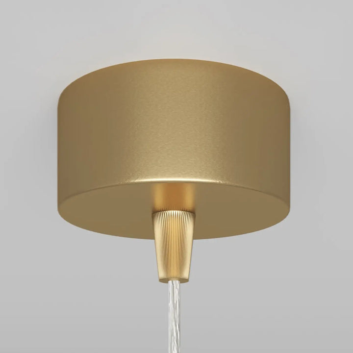 Suspension luminiare gold au-dessus d’un îlot avec tube fin et base conique cannelée en métal doré
