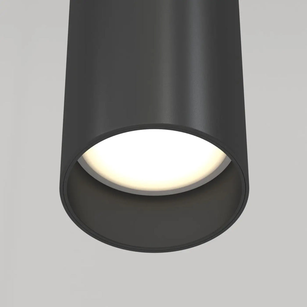 Suspension focus cylindre en métal noir mat avec tube fin et lumière chaude diffusée au-dessus d’un îlot