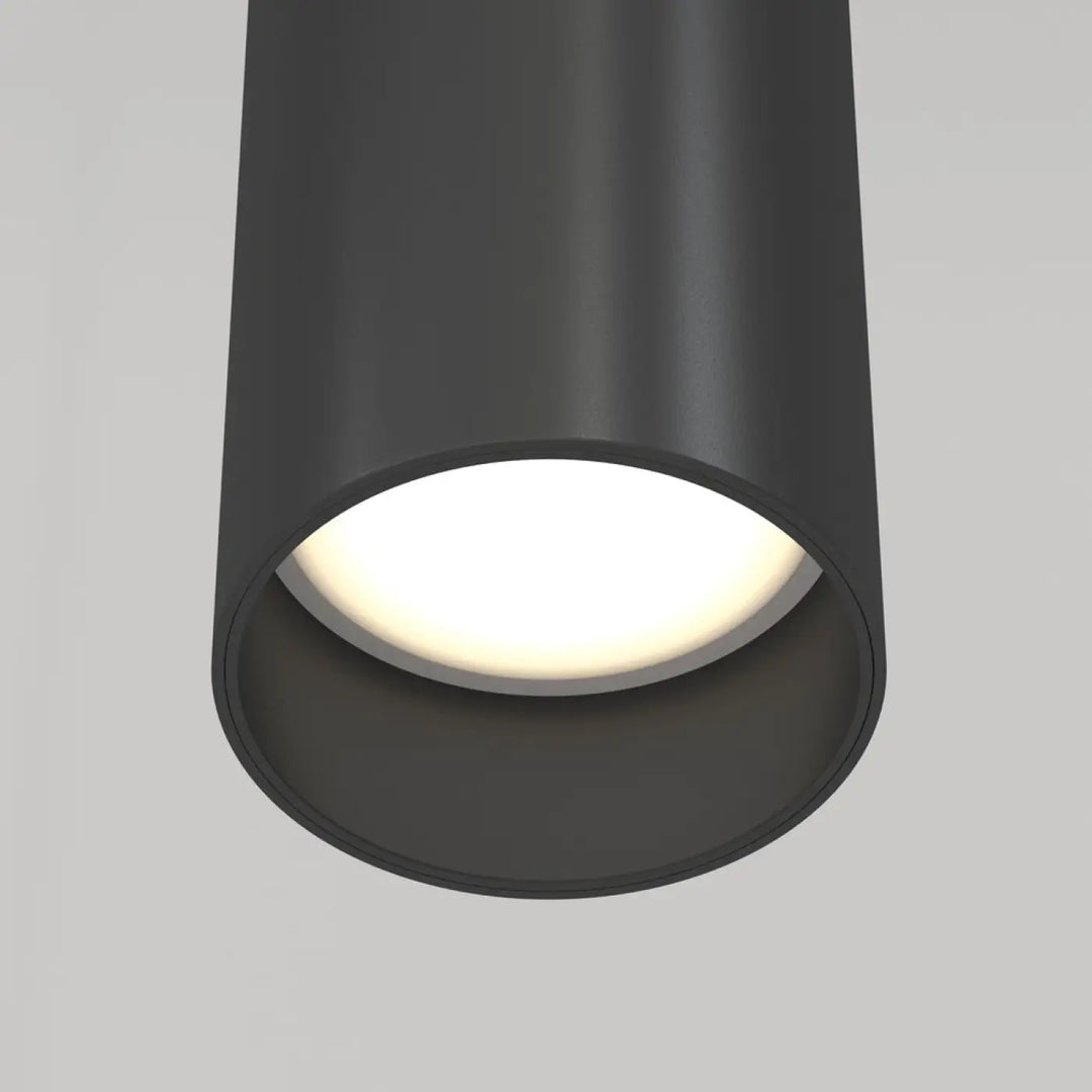 Suspension focus cylindre en métal noir mat avec tube fin et lumière chaude diffusée au-dessus d’un îlot