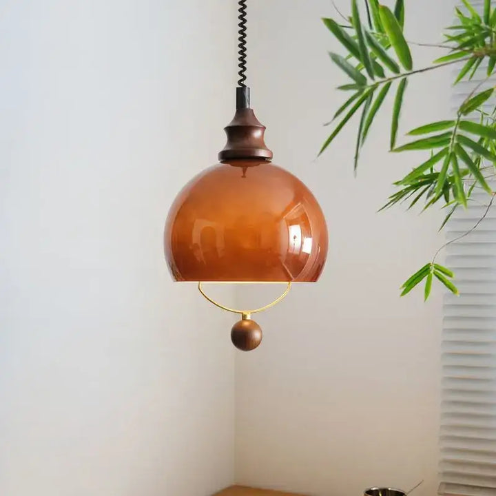 Suspension globe ambrée avec détail doré et boule décorative

