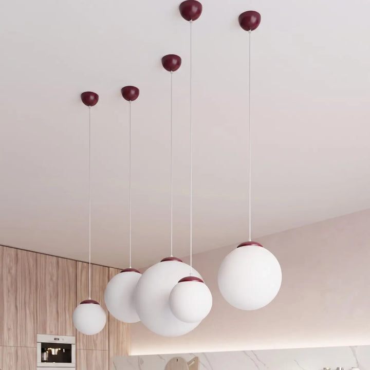 Suspension Ugo à globe en verre blanc et monture bordeaux dans un intérieur contemporain